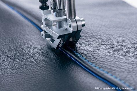 A sewing machine is cutting the blue line.