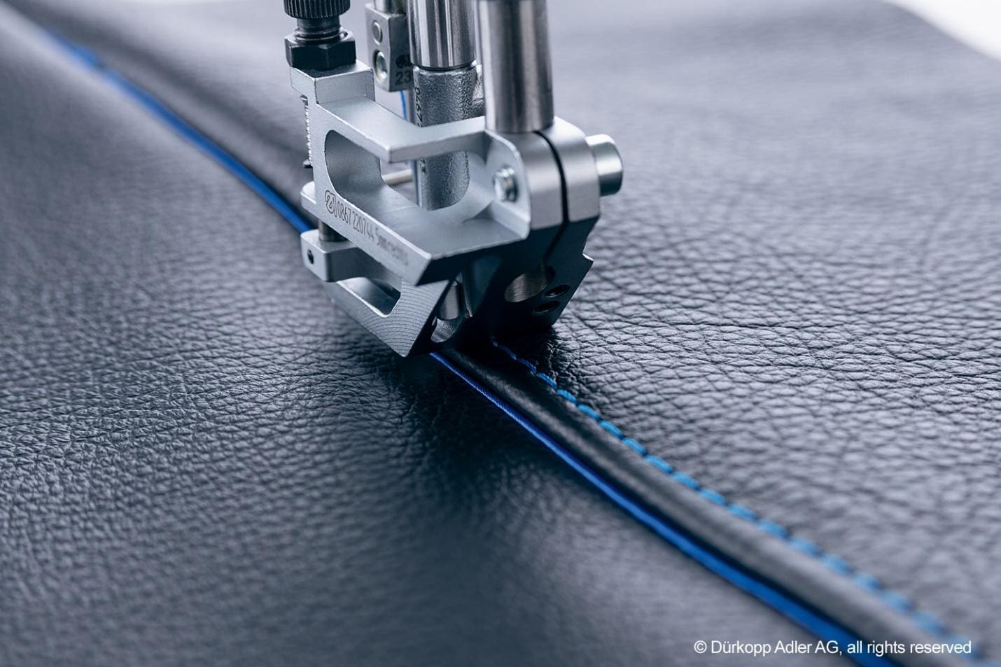 A sewing machine is cutting the blue line.