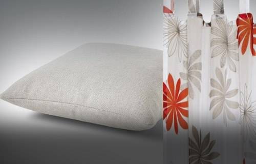 A close-up of a white mattress with a floral curtain in the background.